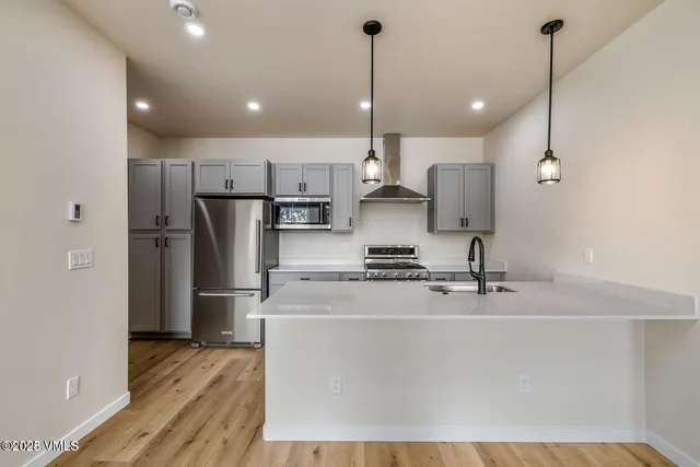 a kitchen with stainless steel appliances granite countertop a refrigerator a sink a stove and a wooden floors