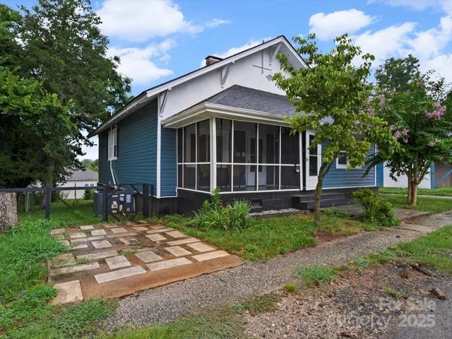 a view of a house with a yard plants and large tree