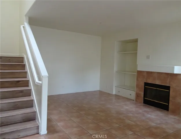a view of an empty room with stairs and a fireplace