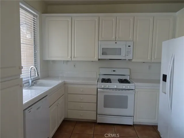 a kitchen with white cabinets and white appliances