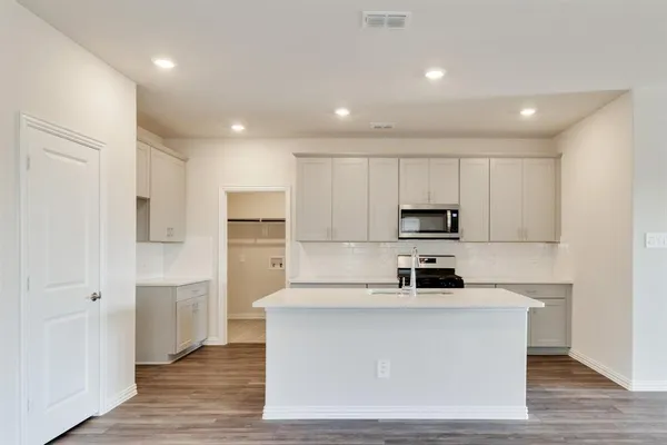 a kitchen with stainless steel appliances granite countertop a white stove top oven a refrigerator and white cabinets