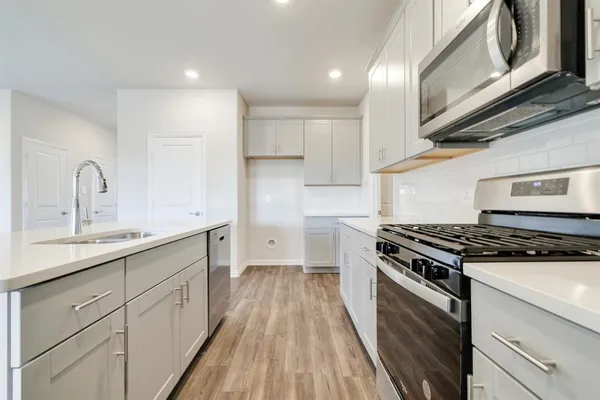 a kitchen with wooden floor a sink a stove and a refrigerator