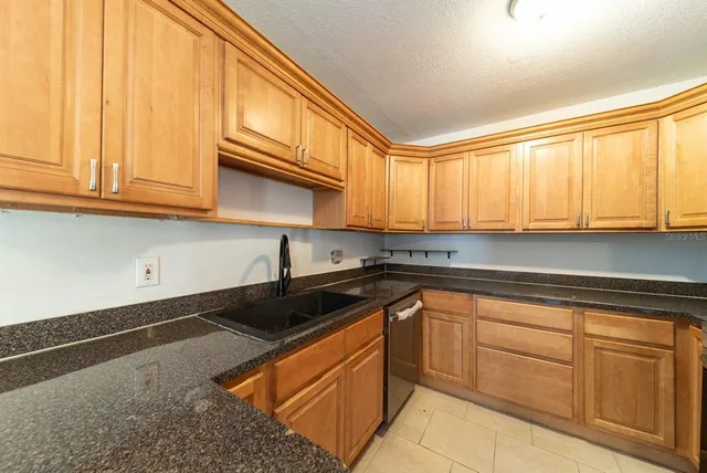 a kitchen with granite countertop cabinets stainless steel appliances a sink and a window
