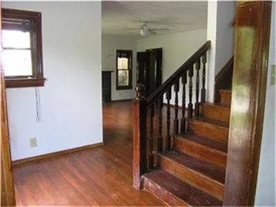 a view of a hallway with wooden floor and staircase