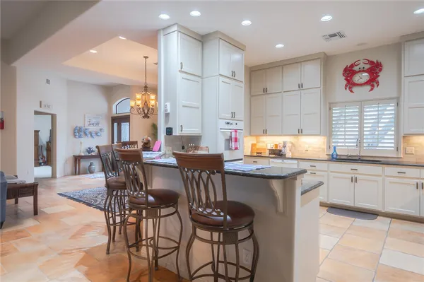 a open kitchen with stainless steel appliances granite countertop a kitchen island a sink a stove a dining table and chairs