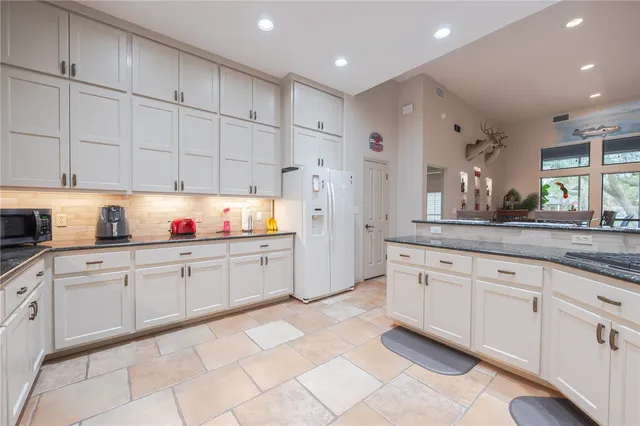 a kitchen with granite countertop white cabinets and white appliances