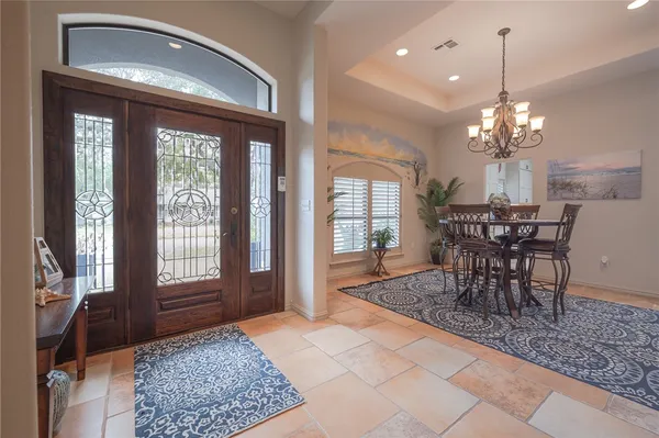 a dining room with chandelier and wooden floor
