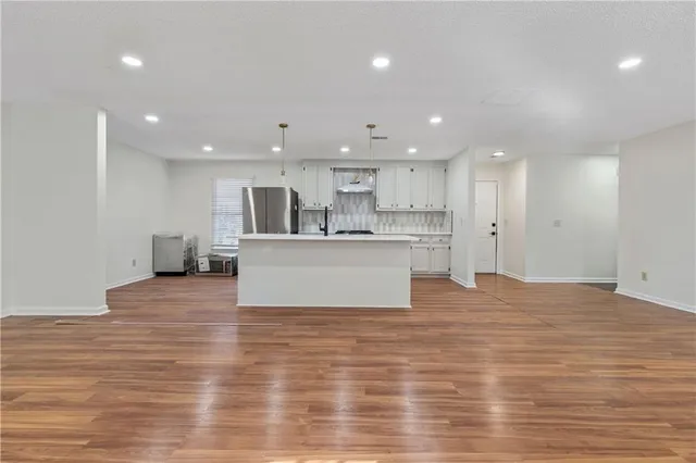 a view of kitchen with kitchen island a sink wooden floor and view living room
