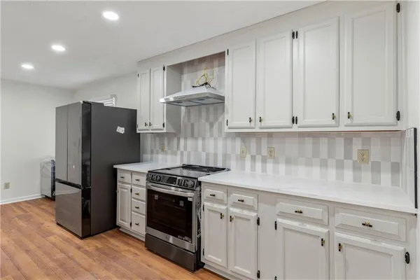 a kitchen with stainless steel appliances white cabinets and a stove top oven