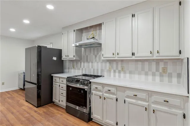 a kitchen with stainless steel appliances white cabinets and a stove top oven