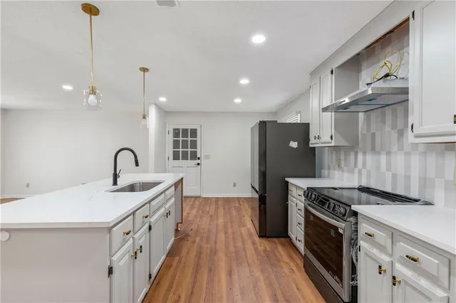 a kitchen with stainless steel appliances granite countertop a sink stove and refrigerator