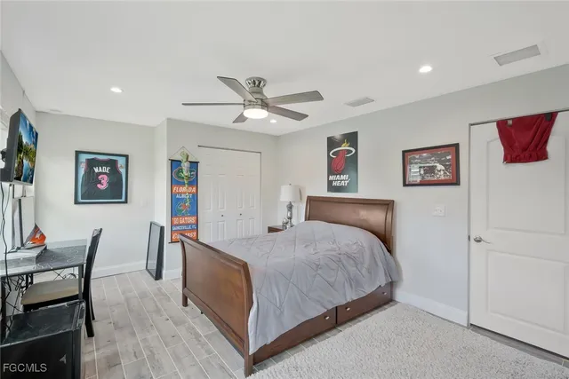 a bedroom with a bed a desk and chair with wooden floor