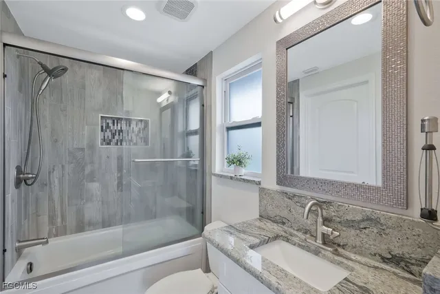 a bathroom with a granite countertop sink mirror and shower