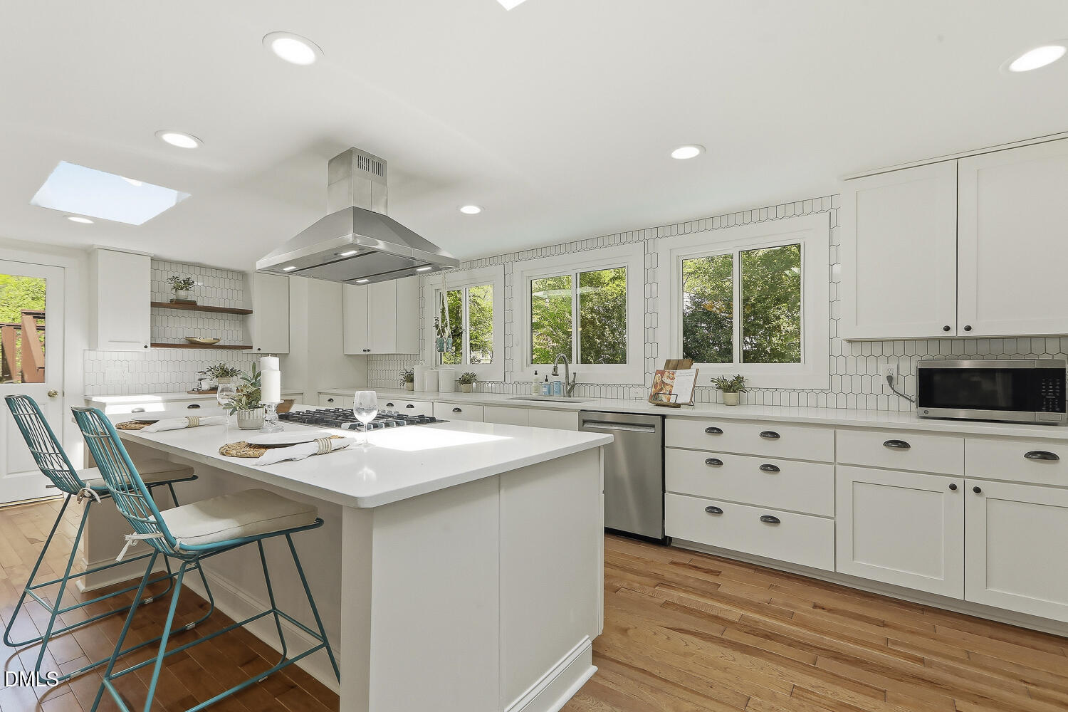 3704 Swann Street Raleigh, NC 27612 - Photo 4 of 21 a kitchen with stainless steel appliances kitchen island granite countertop a stove a sink and white cabinets with wooden floor
