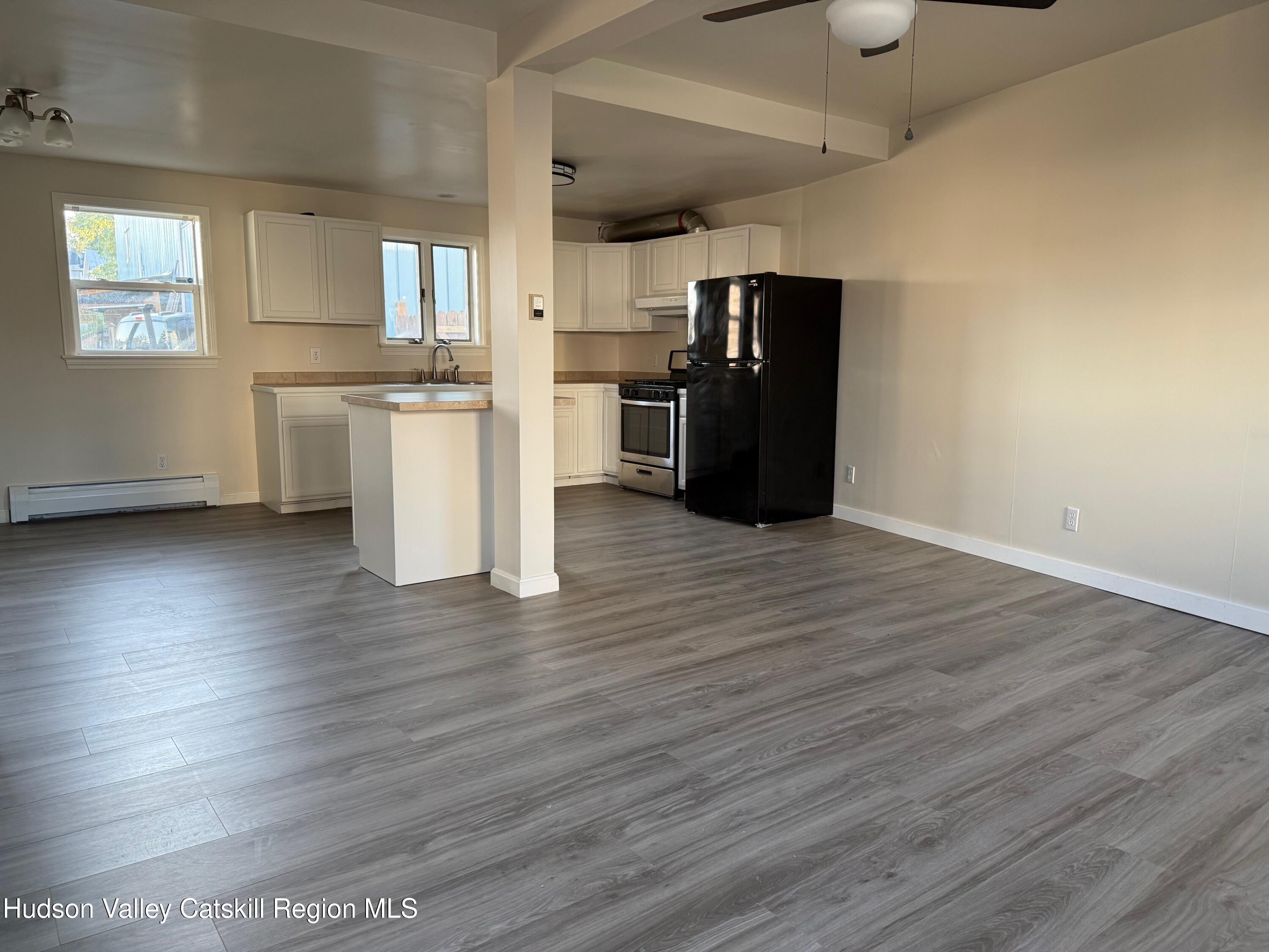 a kitchen with stainless steel appliances wooden floor and a refrigerator