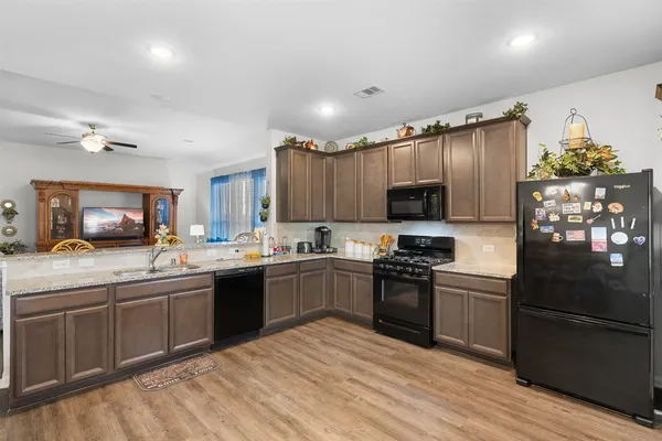 a kitchen with stainless steel appliances granite countertop a sink dishwasher a stove a refrigerator a dining table and chairs with wooden floor