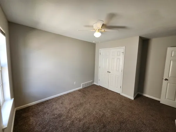 an empty room with a window and a fan