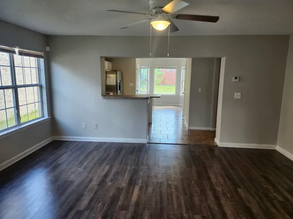 an empty room with wooden floor and windows