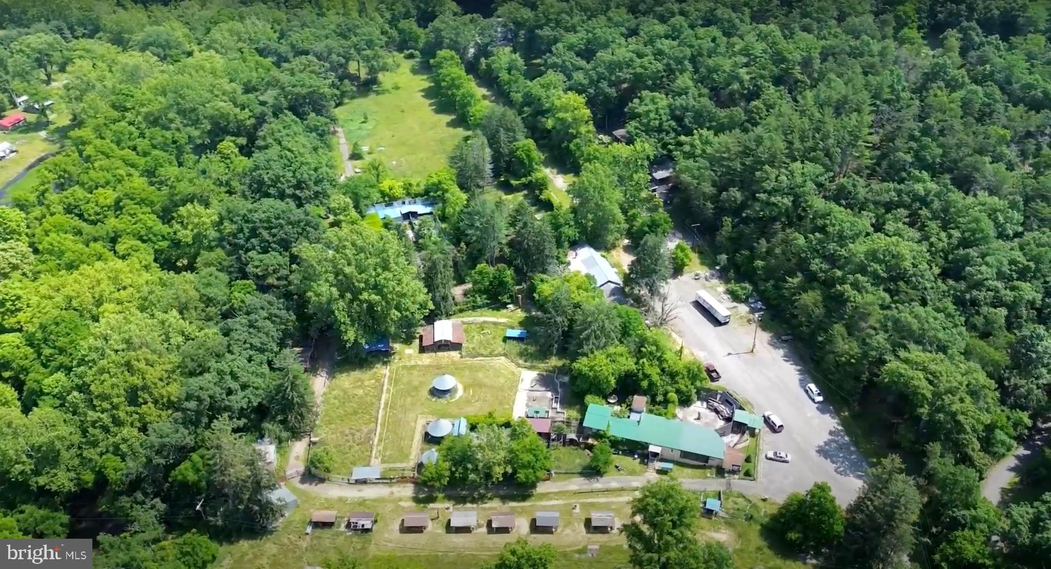 an aerial view of a residential houses with outdoor space and trees all around