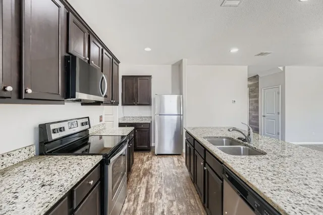 a kitchen with stainless steel appliances granite countertop a sink stove and refrigerator