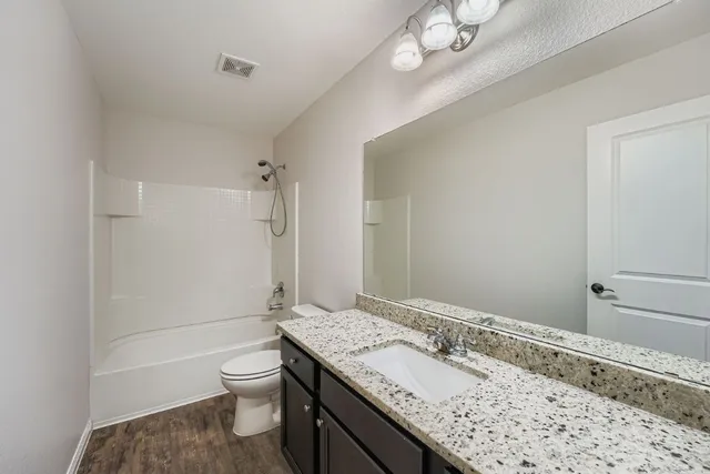 a bathroom with a granite countertop sink a toilet and shower