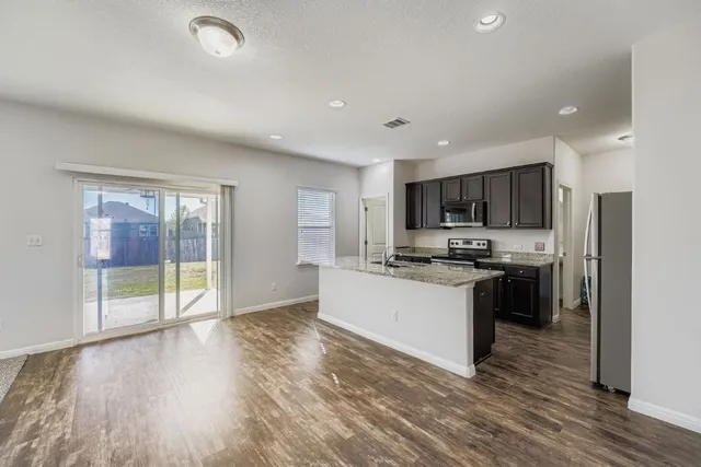 a large kitchen with a center island and wooden floor