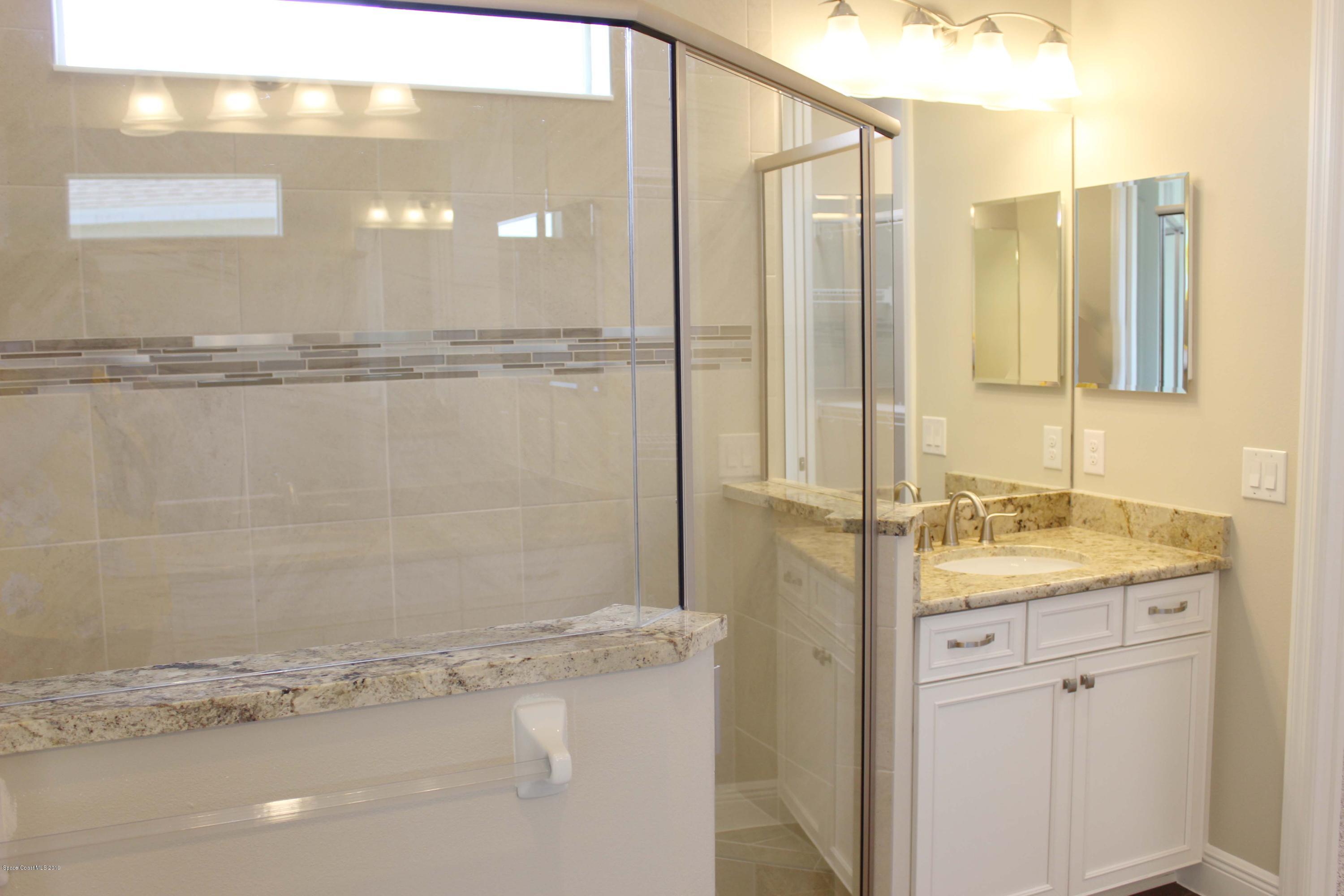 3631 Stabane Place Melbourne, FL 32940 - Photo 12 of 47 a bathroom with a granite countertop sink a mirror and a shower