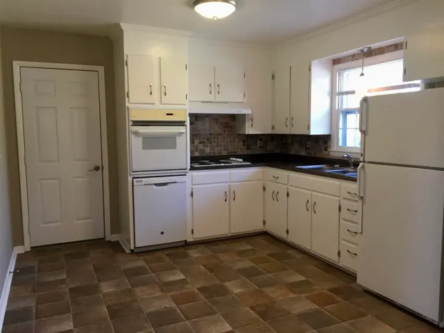 a kitchen with granite countertop white cabinets and white appliances