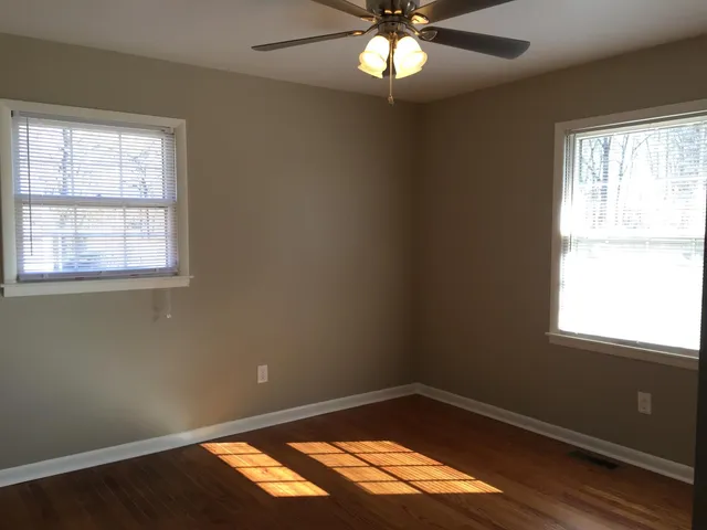 an empty room with a window and wooden floor