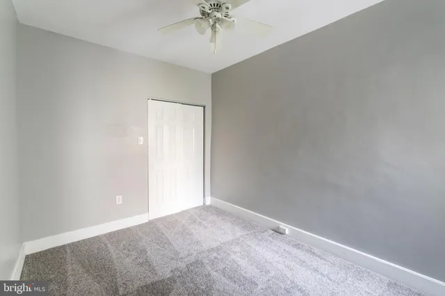 an empty room with a chandelier fan and closet