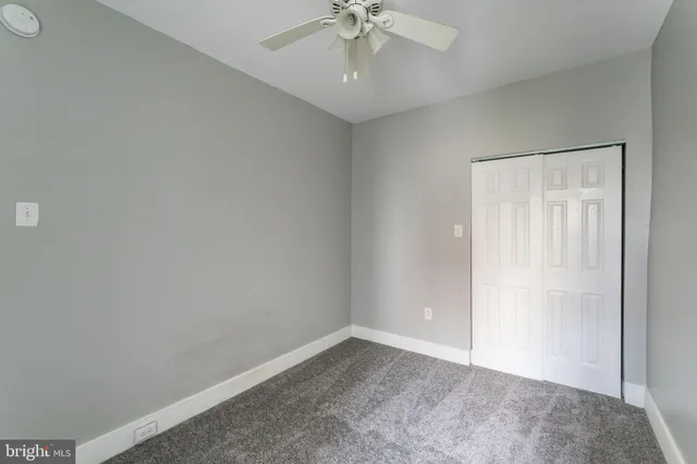 an empty room with a ceiling fan and carpet
