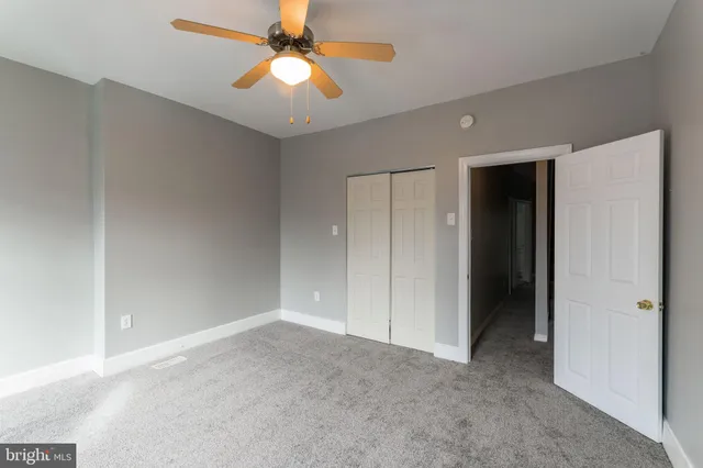 an empty room with closet and a chandelier fan