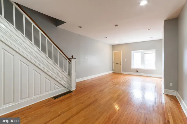 a view of an empty room with wooden floor and stairs