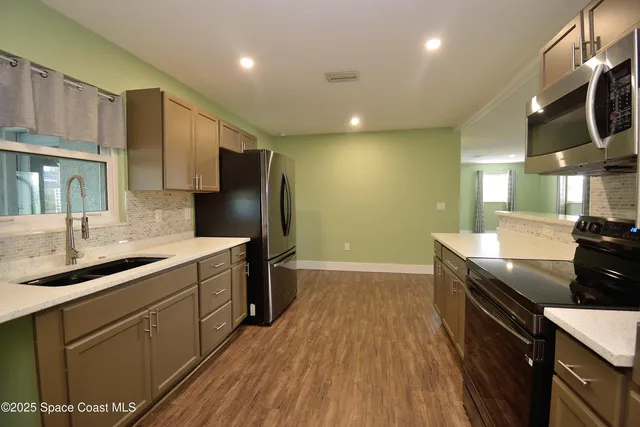 a kitchen with stainless steel appliances granite countertop a sink a stove and a refrigerator