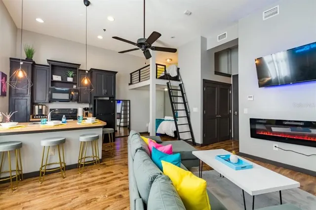 a living room with stainless steel appliances kitchen island granite countertop furniture and a wooden floor