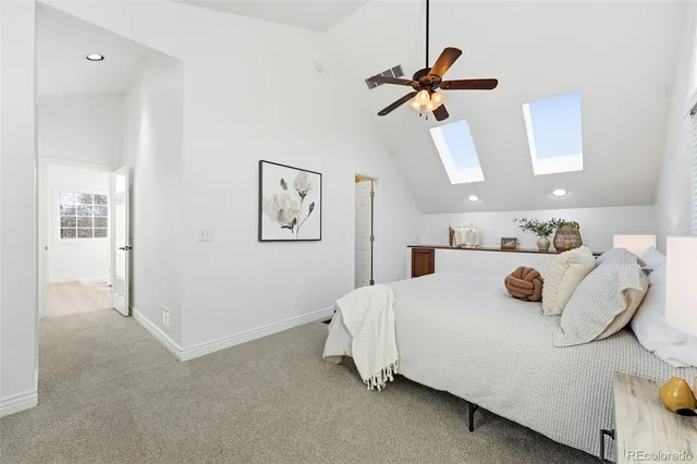 a spacious bedroom with a bed a chandelier and windows