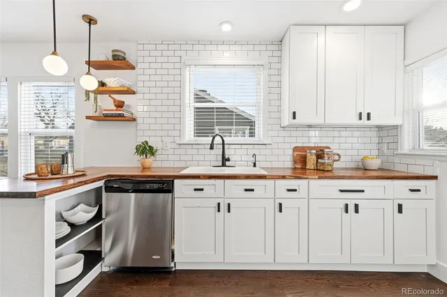 a kitchen with stainless steel appliances granite countertop a sink a stove and a wooden floors