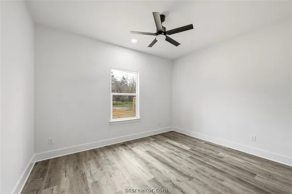 an empty room with a window and a ceiling fan