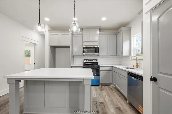 a kitchen with kitchen island a sink stainless steel appliances and cabinets