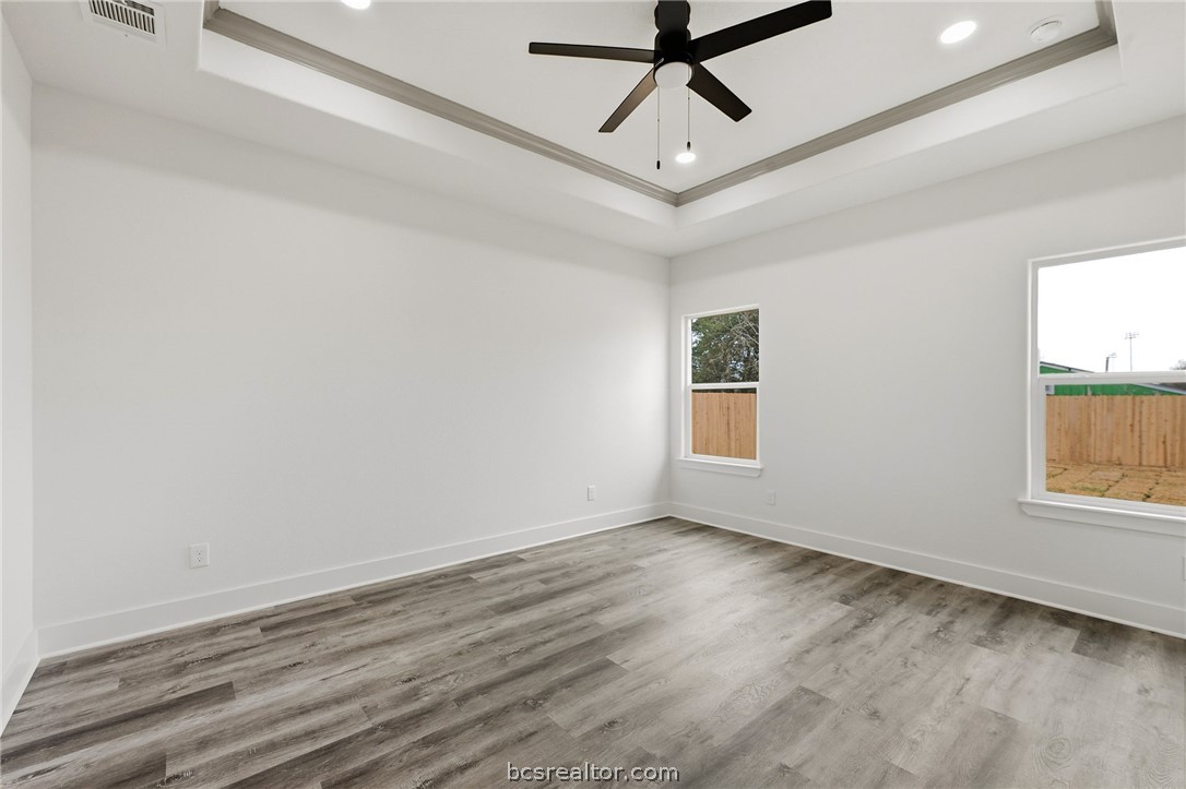 203 Lock Lane Bryan, TX 77803 - Photo 10 of 22 an empty room with wooden floor ceiling fan and windows
