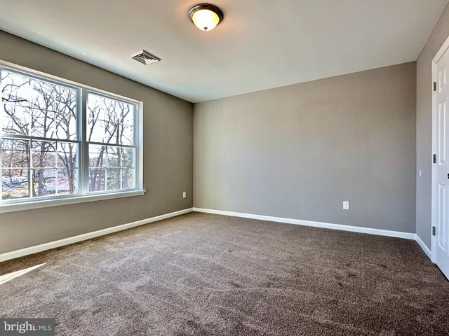 a view of an empty room with closet and a window