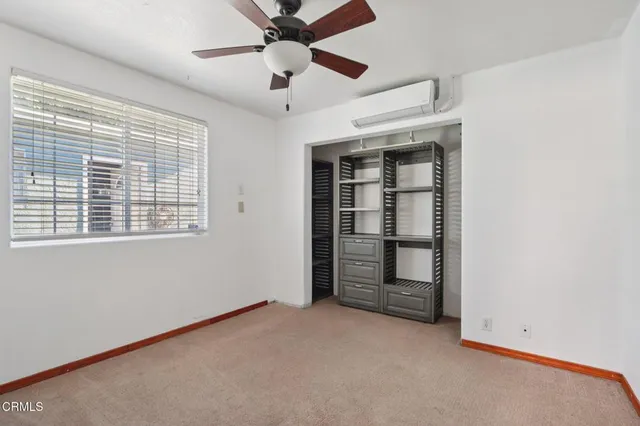 an empty room with a window and ceiling fan