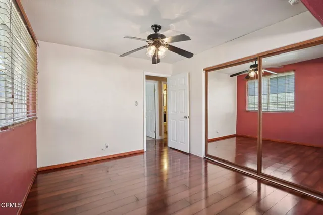 a view of empty room with wooden floor and fan