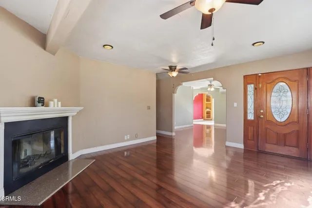 a view of an empty room with wooden floor fireplace and a window