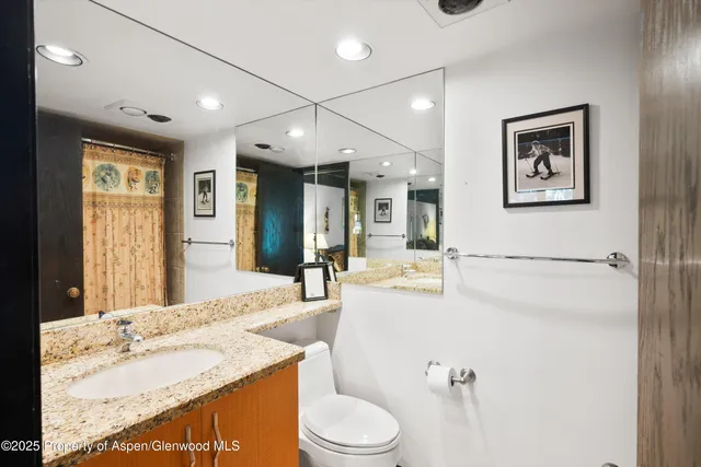 a bathroom with a granite countertop sink mirror vanity and toilet