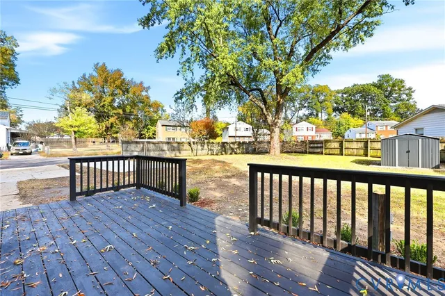 a view of deck with wooden floor and fence next to a yard