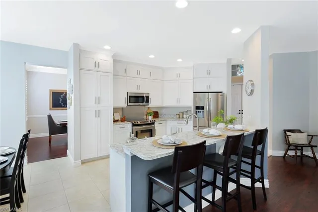 a kitchen with stainless steel appliances a dining table chairs refrigerator and microwave