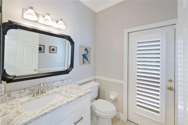 a bathroom with a granite countertop sink toilet and mirror