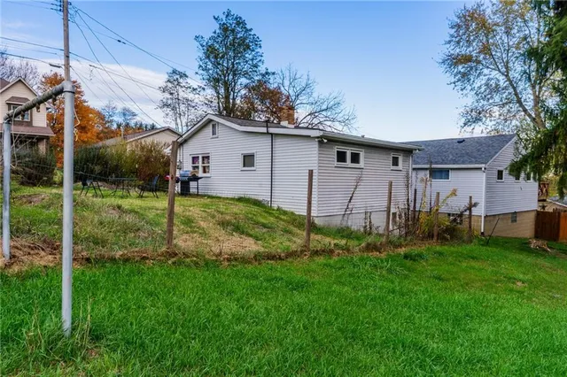 a view of a yard in front of a house with plants and large tree