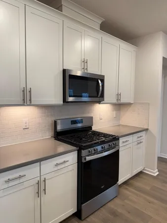 a kitchen with cabinets stainless steel appliances and a wooden floor